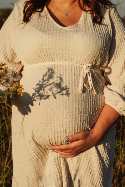 A baby bump with a bouquet of flowers in the sunset at a photo shoot for pregnant women in Dresden